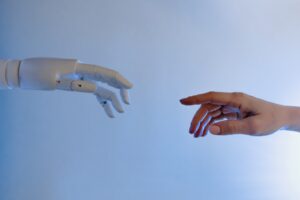 uma mão robotica tentando tocar uma mão humana